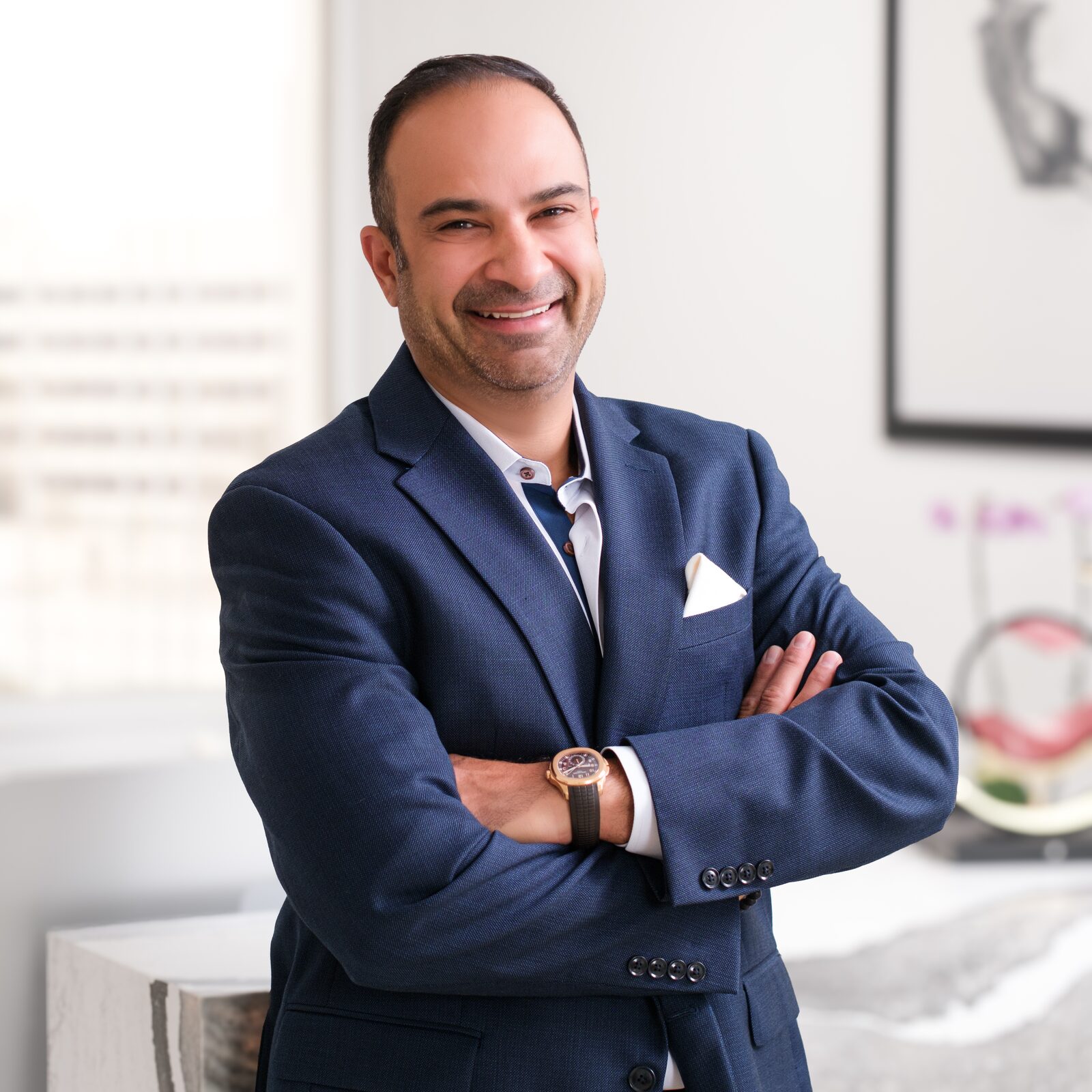 Board-certified plastic surgeon Dr. Ali Roham in a navy suit