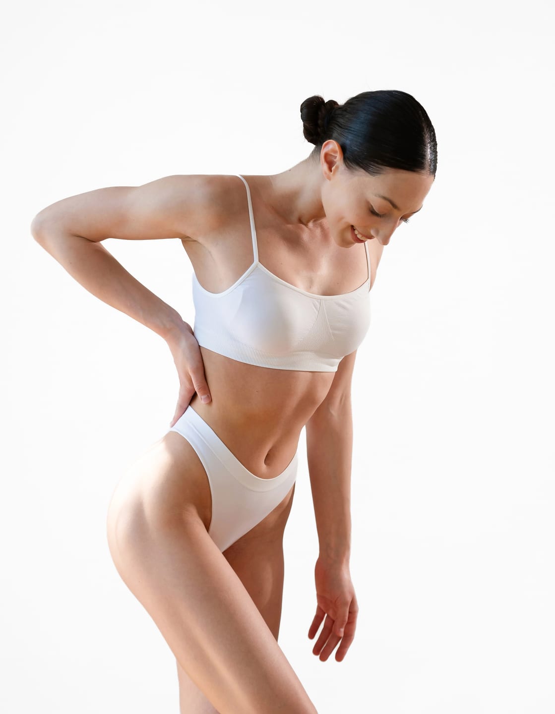 Woman in a white underwear set leaning to one side with a hand on her hip