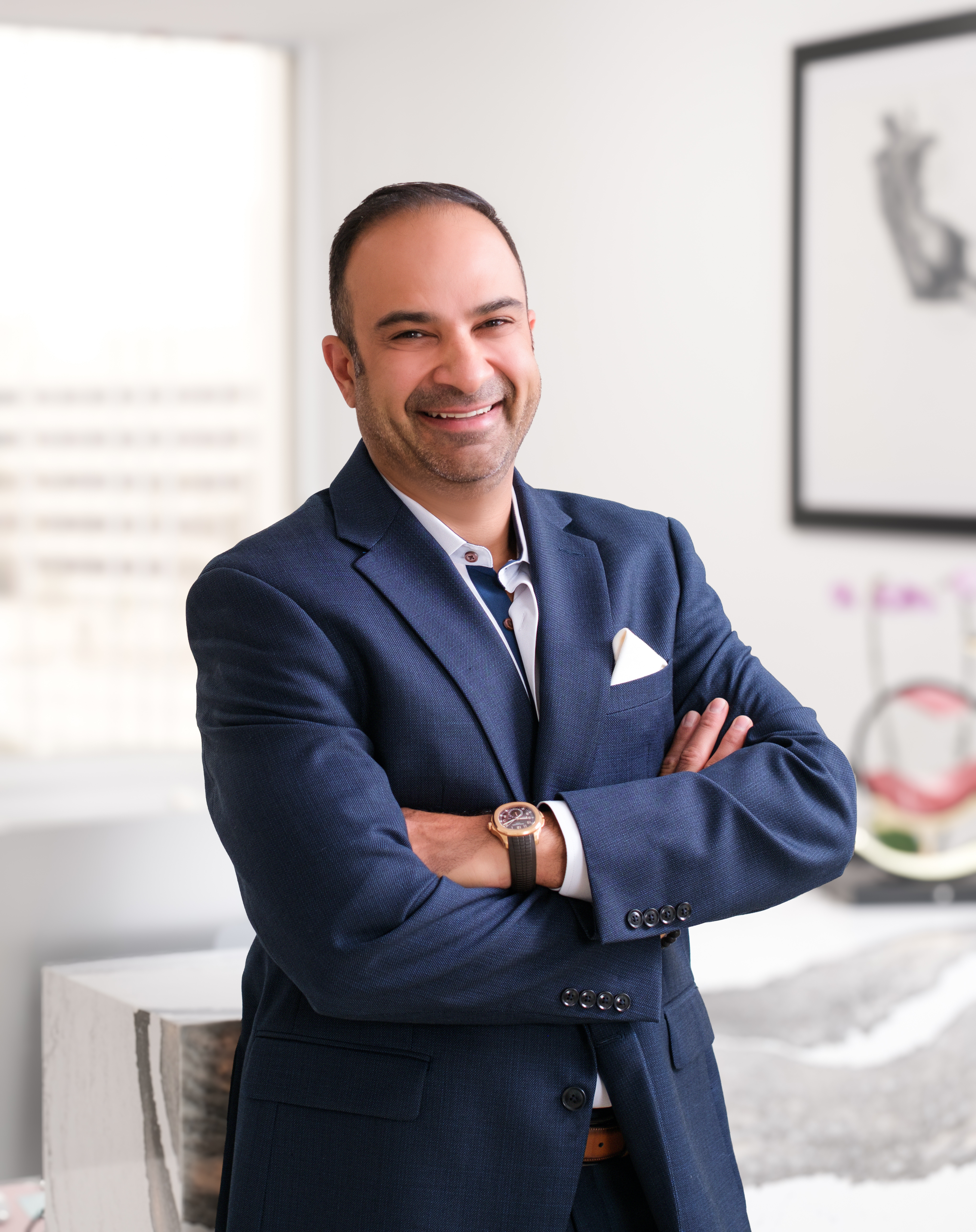 Dr. Ali Roham standing with his arms crossed in black Roham Plastic Surgery scrubs